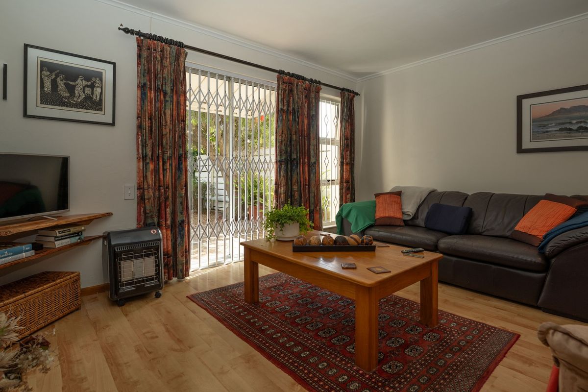A comfortable living room featuring laminate flooring and a sliding door with a security gate, providing direct access to the outdoor area.