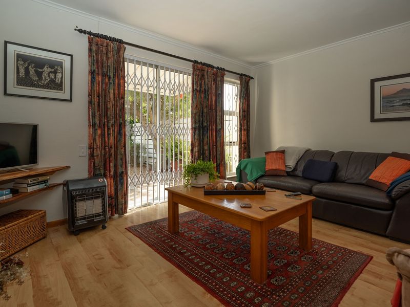 A comfortable living room featuring laminate flooring and a sliding door with a security gate, providing direct access to the outdoor area.