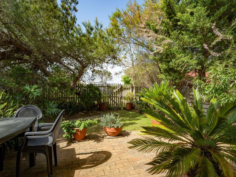 A private, well-established garden featuring brick paving, mature trees, and a timber fence, providing a peaceful outdoor retreat.