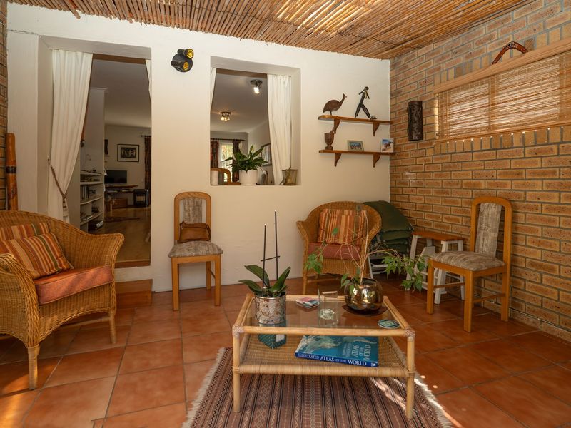 A rustic covered patio featuring exposed brick walls, terracotta tiling, and a natural bamboo ceiling, providing a cozy transition to the interior living space.