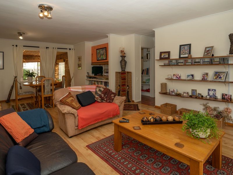 Open plan living and dining area featuring laminate flooring, built-in wall shelving, and direct access to an outdoor patio space.