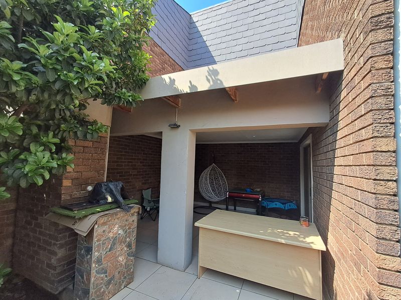 A covered outdoor patio area featuring brick walls, tiled flooring, and a stone-clad feature pillar, offering a functional space for outdoor living.