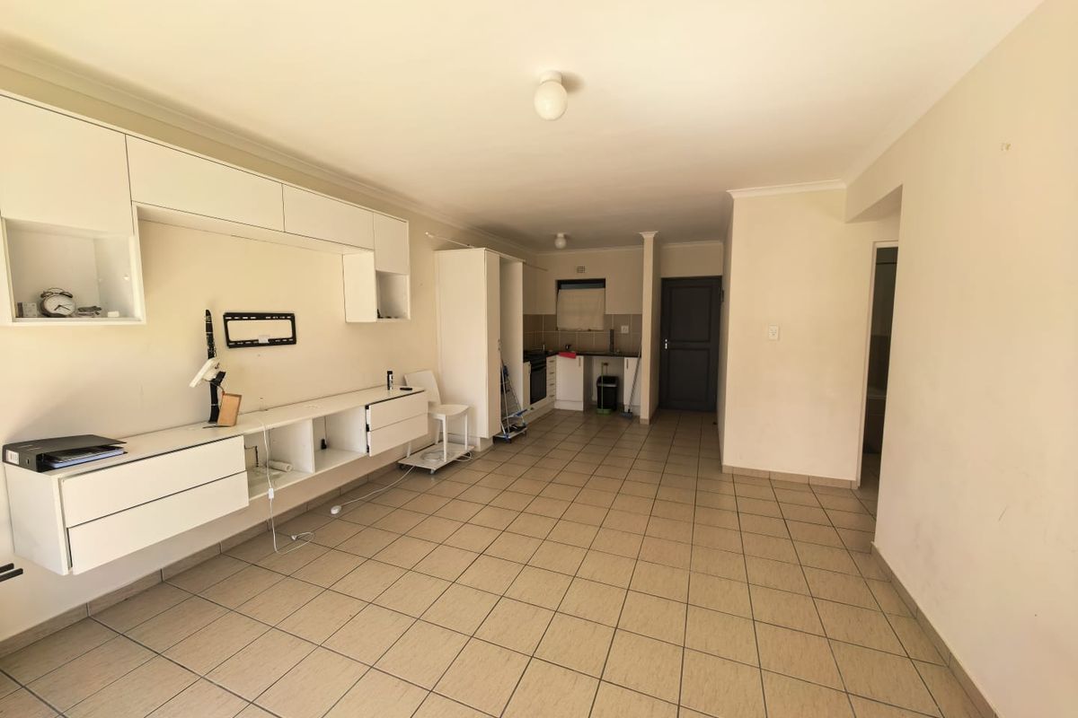 Open-plan living and kitchen area featuring tiled flooring, built-in cabinetry, and a functional kitchen layout with integrated oven and hob.