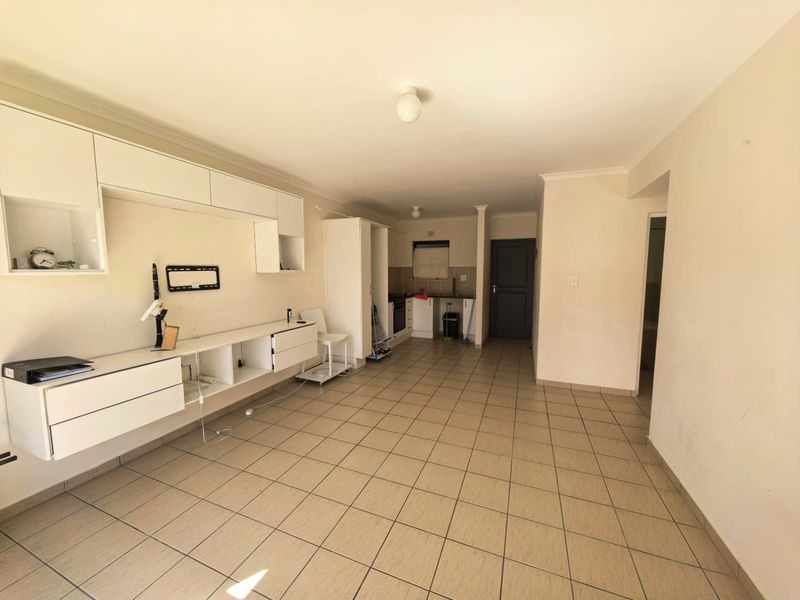 Open-plan living and kitchen area featuring tiled flooring, built-in cabinetry, and a functional kitchen layout with integrated oven and hob.