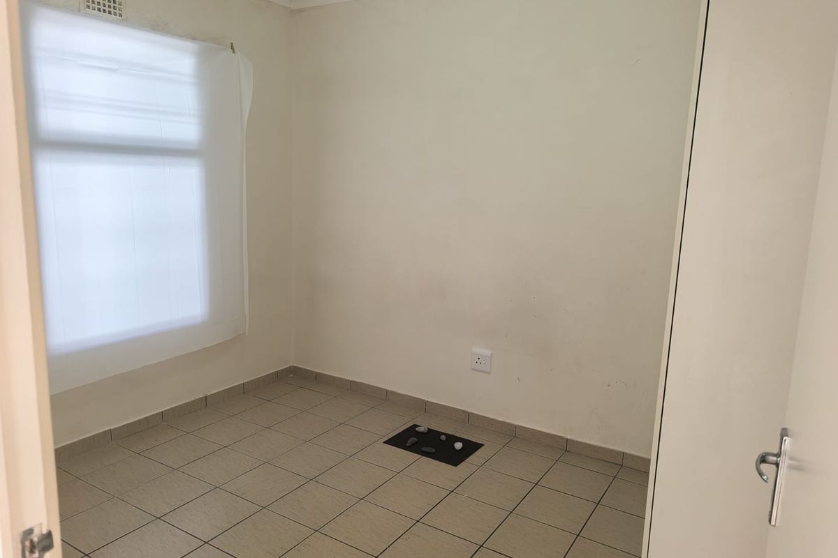 An empty bedroom featuring tiled flooring, a built-in cupboard, and neutral wall finishes, offering a blank canvas for personalization.
