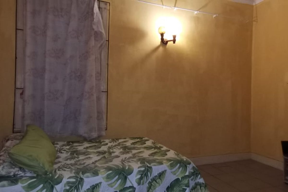A bedroom featuring tiled flooring and a wall-mounted light fixture, requiring cosmetic updates to the wall finishes.