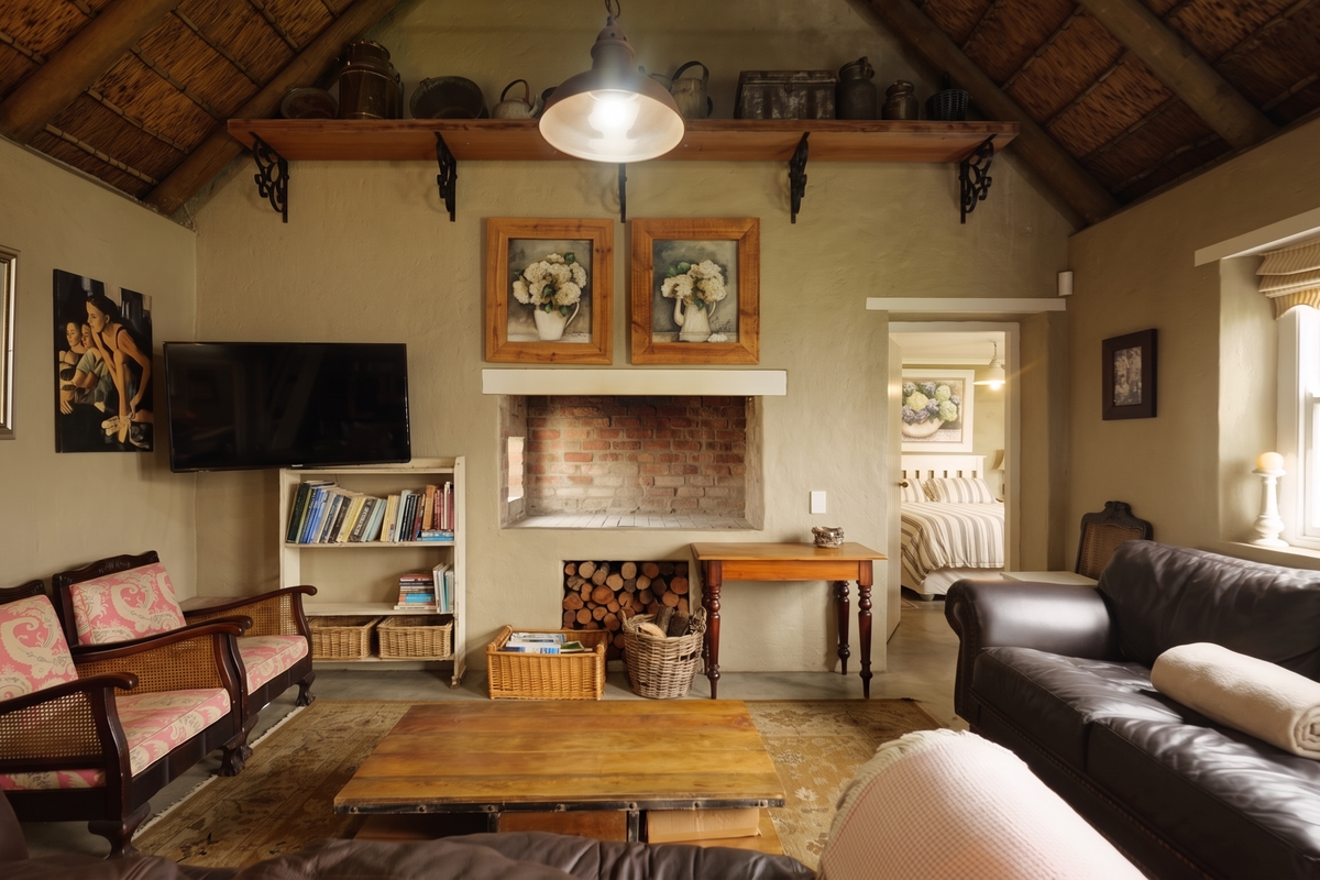 Cozy living room featuring a traditional thatched roof with exposed timber rafters and a central brick fireplace, creating a warm and rustic atmosphere.