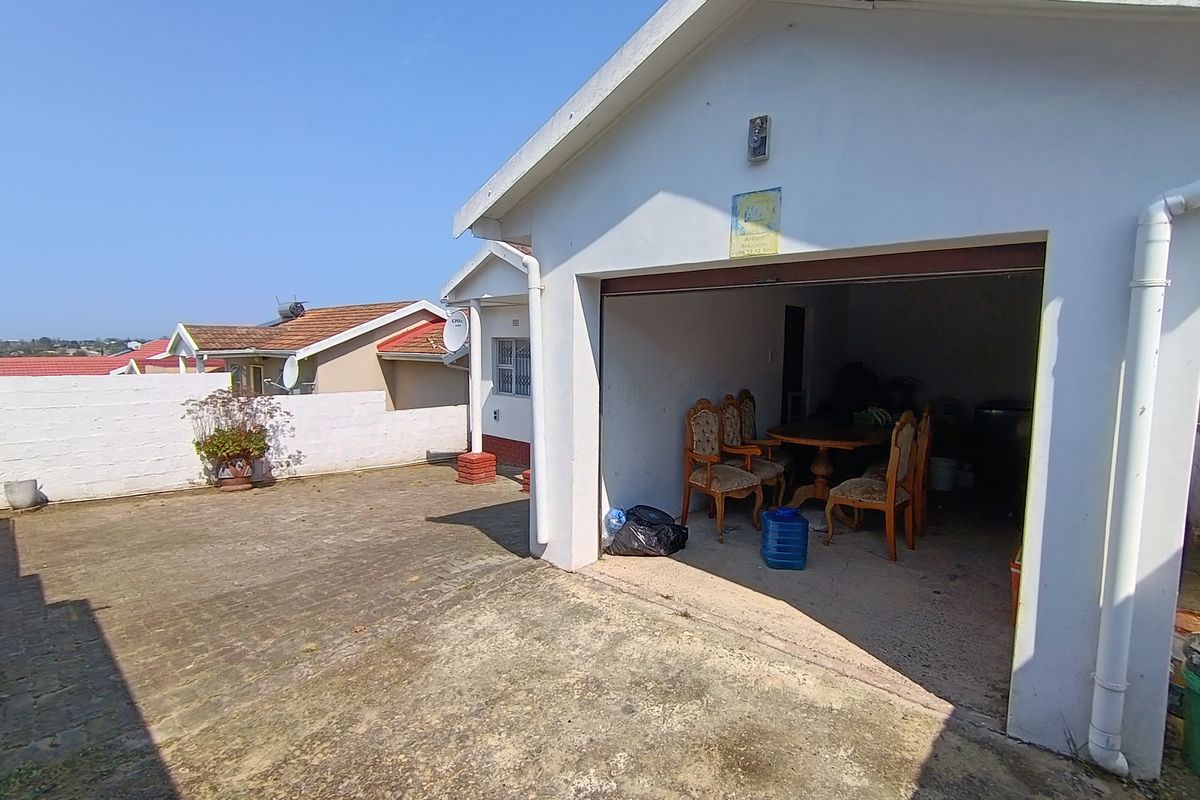 A detached garage structure with a concrete driveway and exterior lighting, showing signs of weathering and wear.