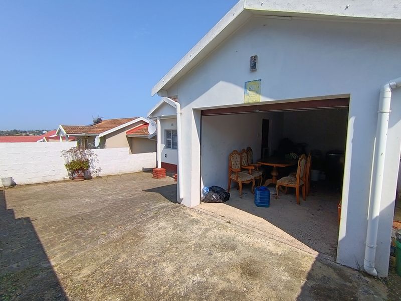 A detached garage structure with a concrete driveway and exterior lighting, showing signs of weathering and wear.