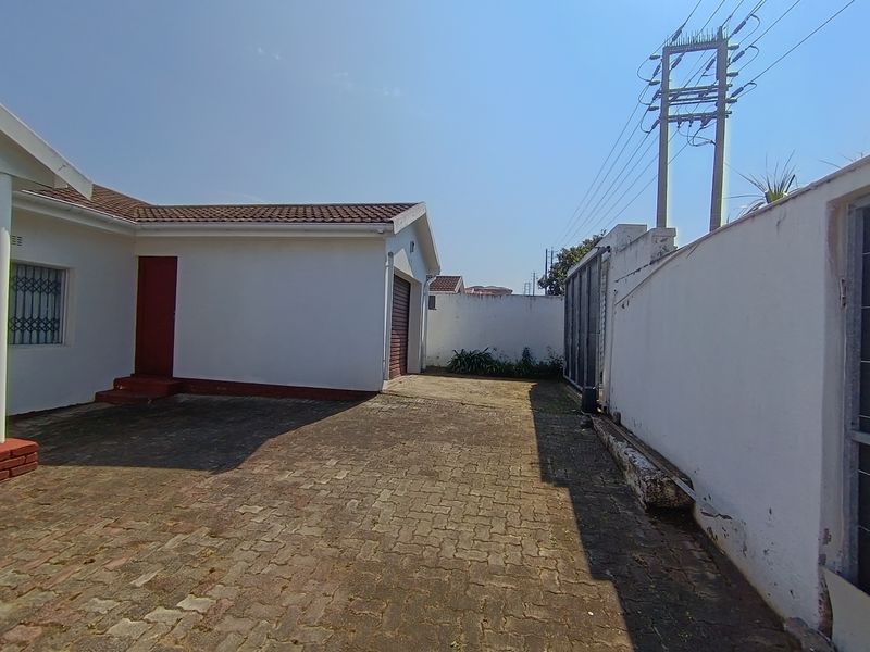 Rear exterior view showing a paved driveway, perimeter wall, and garage access point.