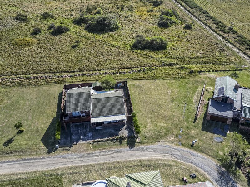Aerial view of a residential property featuring a tiled roof dwelling, private swimming pool, and surrounding landscaped grounds in a rural setting.