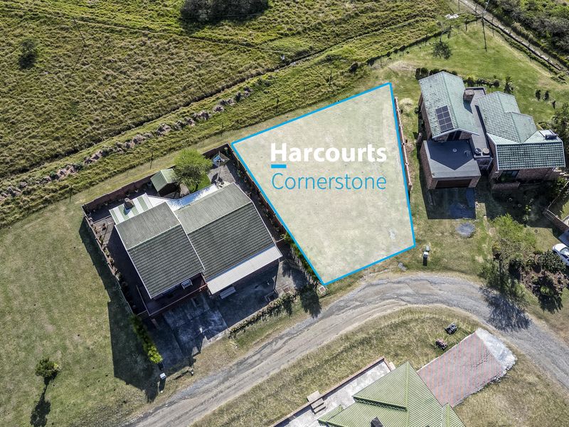 An aerial view of a vacant residential plot situated within an established neighborhood, highlighting the available land and surrounding property context.
