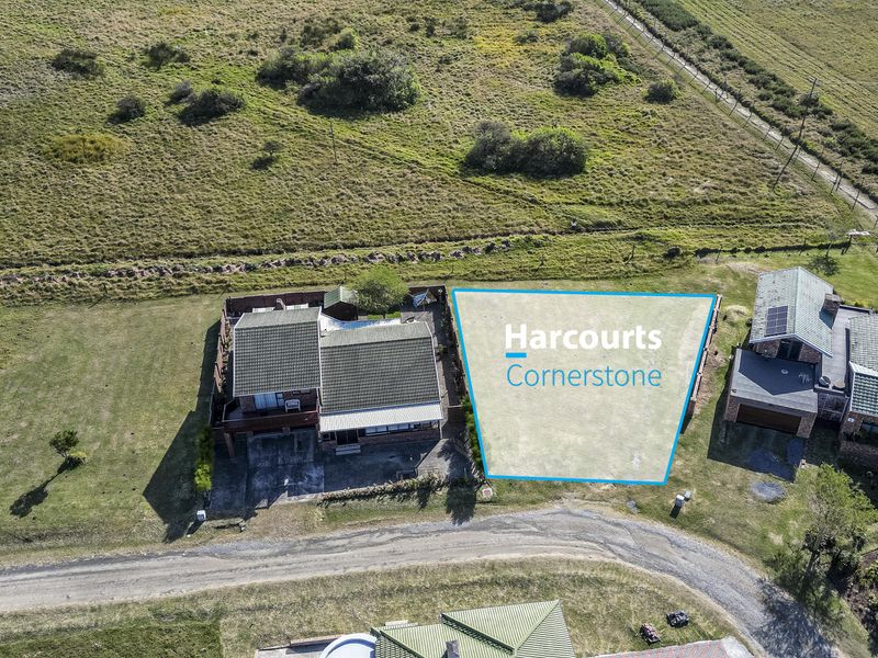 Aerial view of a vacant residential plot situated between existing homes, offering a clear space for potential development.