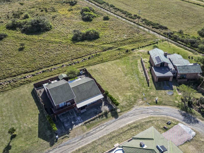 Aerial view of residential properties situated on a large plot of land with established lawns, fencing, and tiled roof structures.