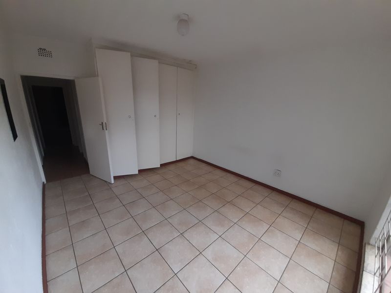 An empty bedroom featuring tiled flooring and built-in cupboards, providing a blank canvas for personalization.