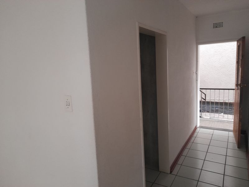 A simple, empty hallway featuring tiled flooring and access to an exterior balcony area.