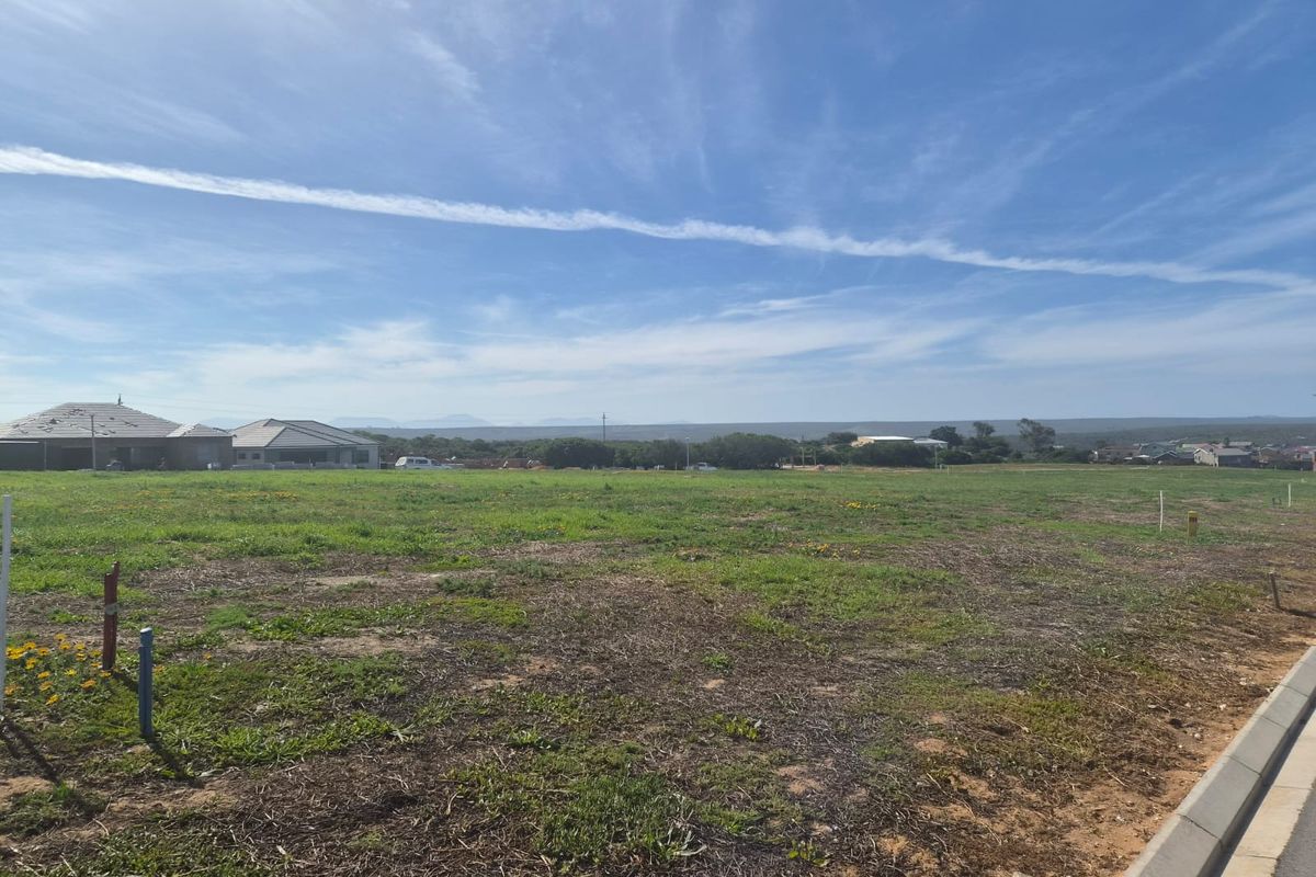 A vacant residential plot of land featuring level ground, established kerbing, and surrounding neighborhood views.