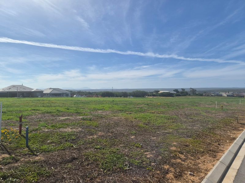A vacant residential plot of land featuring level ground, established kerbing, and surrounding neighborhood views.