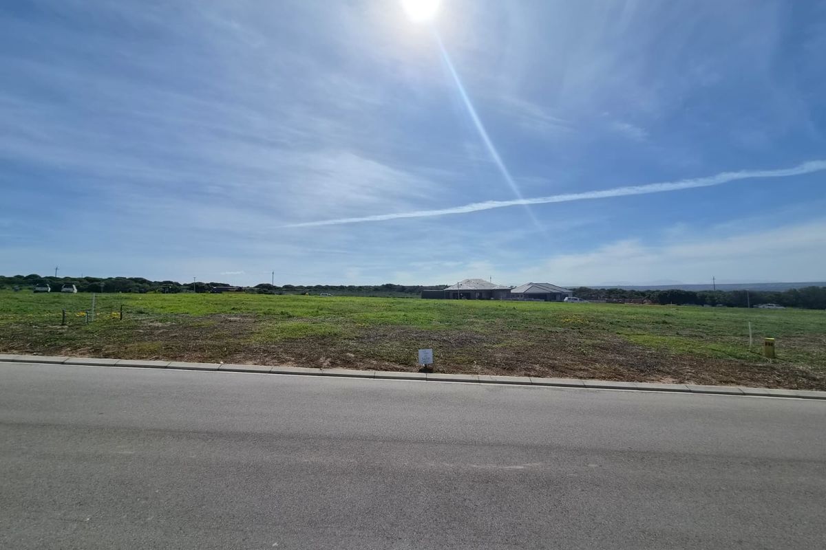 A wide-angle view of a vacant residential plot of land situated along a paved road, ready for development.