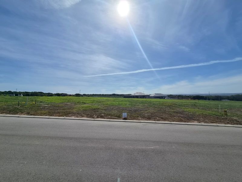 A wide-angle view of a vacant residential plot of land situated along a paved road, ready for development.