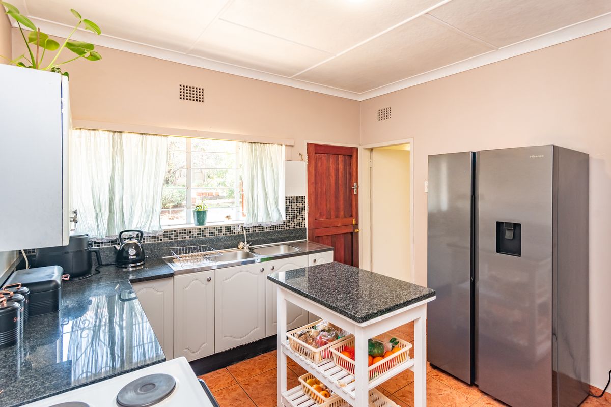 Functional kitchen featuring granite countertops, mosaic tile backsplash, double sink, and tiled flooring, offering a practical layout for daily meal preparation.