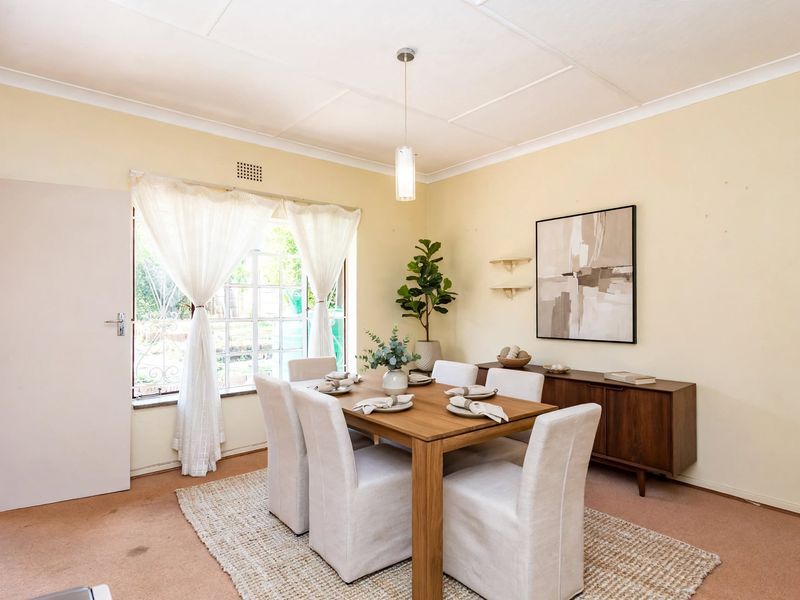 A dining room featuring a pendant light, large window, and carpeted flooring, offering a functional space for family meals.