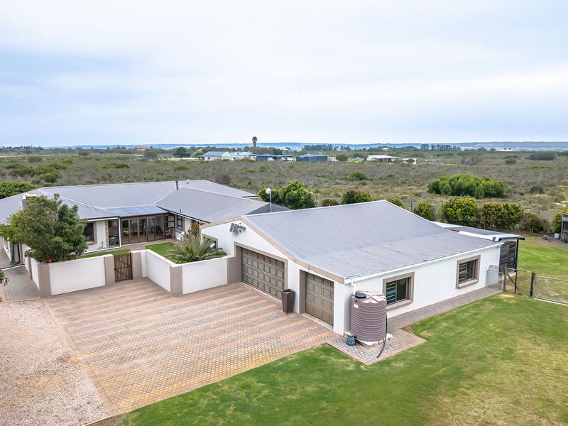 Aerial view of a well-maintained small holding featuring a spacious residence with a double garage, paved driveway, and expansive surrounding garden grounds.
