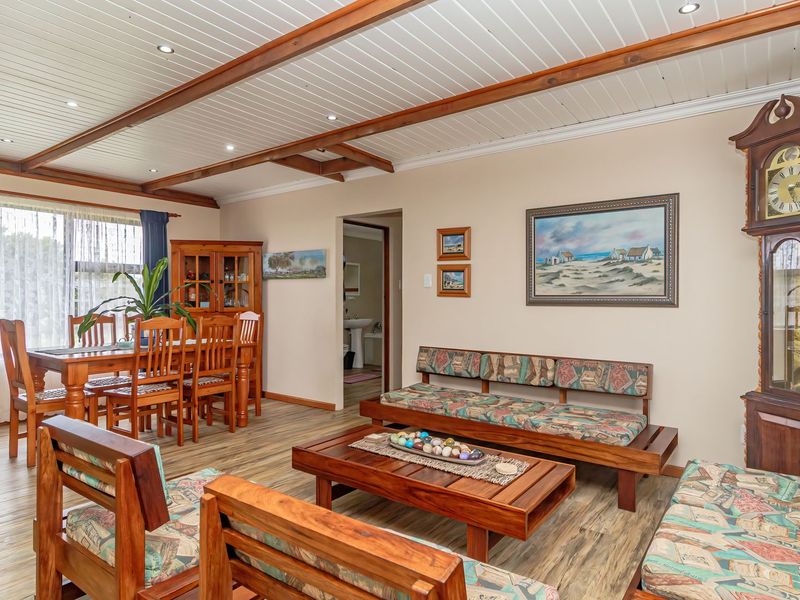 Spacious open-plan living and dining area featuring wood-look laminate flooring, exposed timber ceiling beams, and recessed lighting.