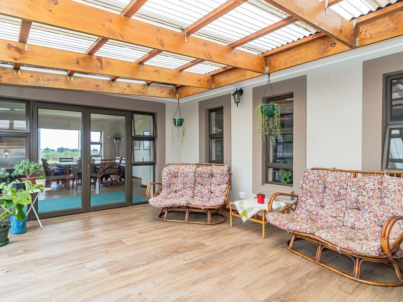 A well-maintained covered patio featuring a timber pergola, polycarbonate roofing, and large aluminium sliding doors providing seamless access to the interior living space.