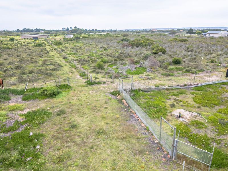 Aerial view of a large small holding property featuring expansive natural land, wire perimeter fencing, and gated access points.