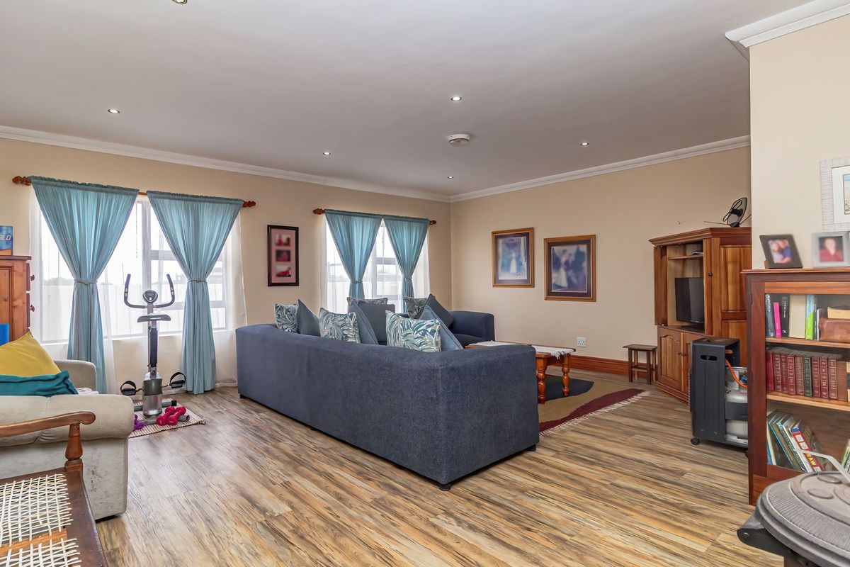 Spacious living room featuring durable laminate flooring, recessed downlighting, and coved cornicing, offering a comfortable and well-maintained area for relaxation.