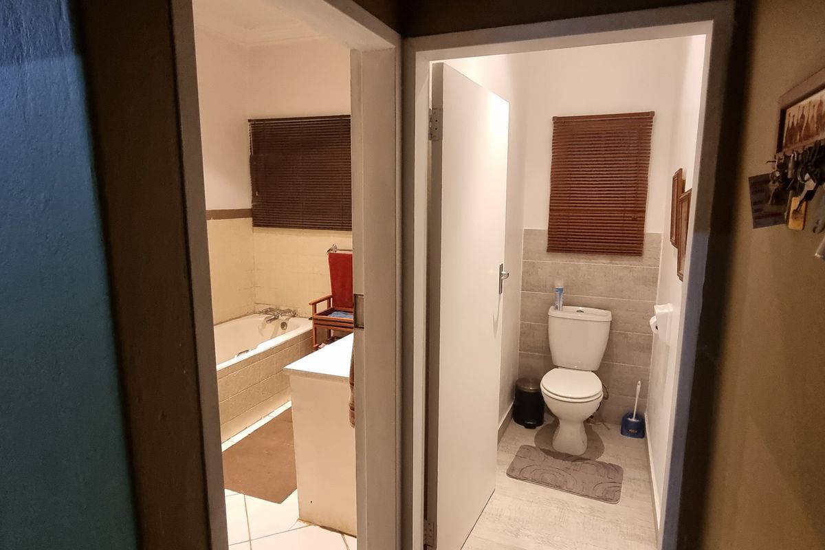 A functional bathroom and separate toilet area featuring tiled finishes, a bathtub, and neutral wall tones, providing a practical layout for the home.