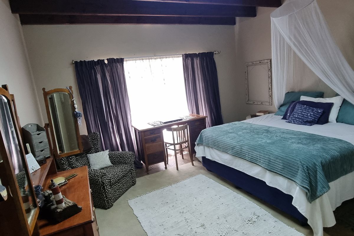 Spacious bedroom featuring exposed timber ceiling beams and natural light, offering a comfortable and rustic atmosphere.