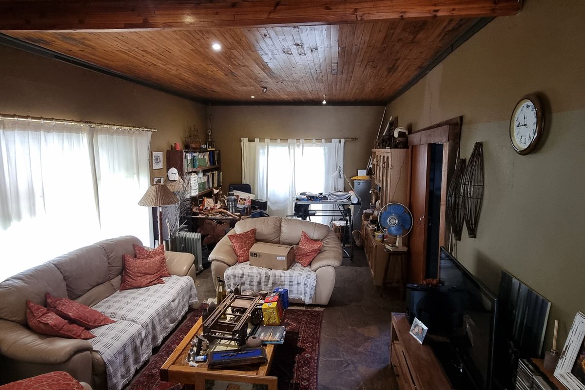 A living room featuring a rustic timber ceiling with exposed beams and stone flooring, offering a traditional farm-style aesthetic with potential for modernization.