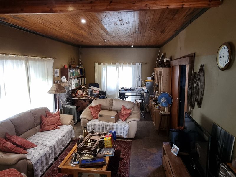 A living room featuring a rustic timber ceiling with exposed beams and stone flooring, offering a traditional farm-style aesthetic with potential for modernization.