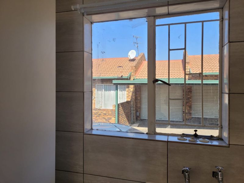 A view from a tiled bathroom window looking out towards neighboring townhouse units and garages.