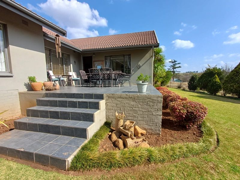 A spacious tiled patio area featuring brick retaining walls and steps, providing an outdoor entertainment space overlooking the garden.