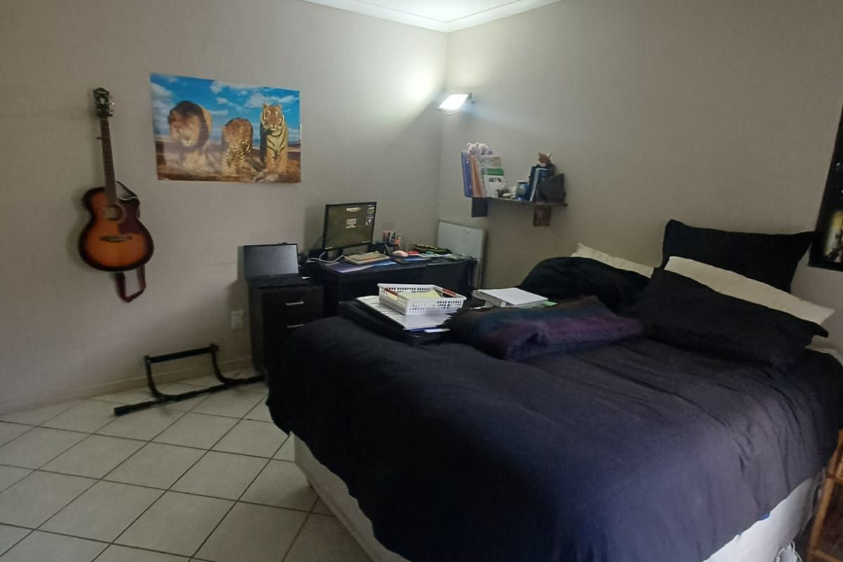 A functional bedroom featuring tiled flooring and recessed ceiling lighting, providing a neutral base for personalization.