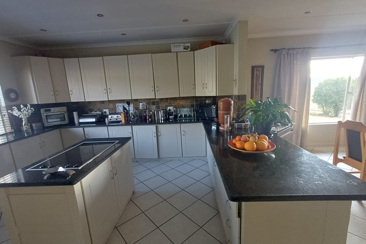 Spacious kitchen featuring extensive built-in cabinetry, granite countertops, a central island with a hob, and ceramic tile flooring.