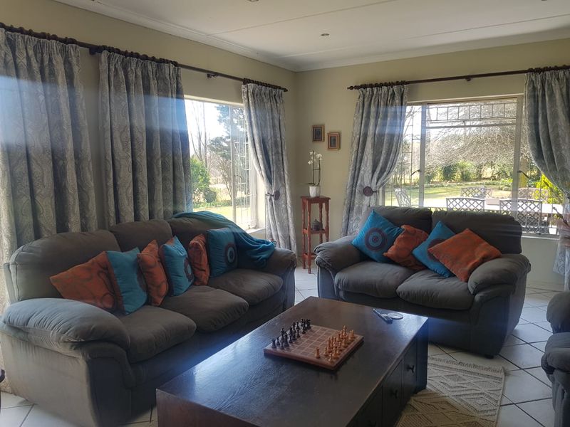 A comfortable living room featuring tiled flooring, recessed lighting, and large windows that provide ample natural light and views of the garden.