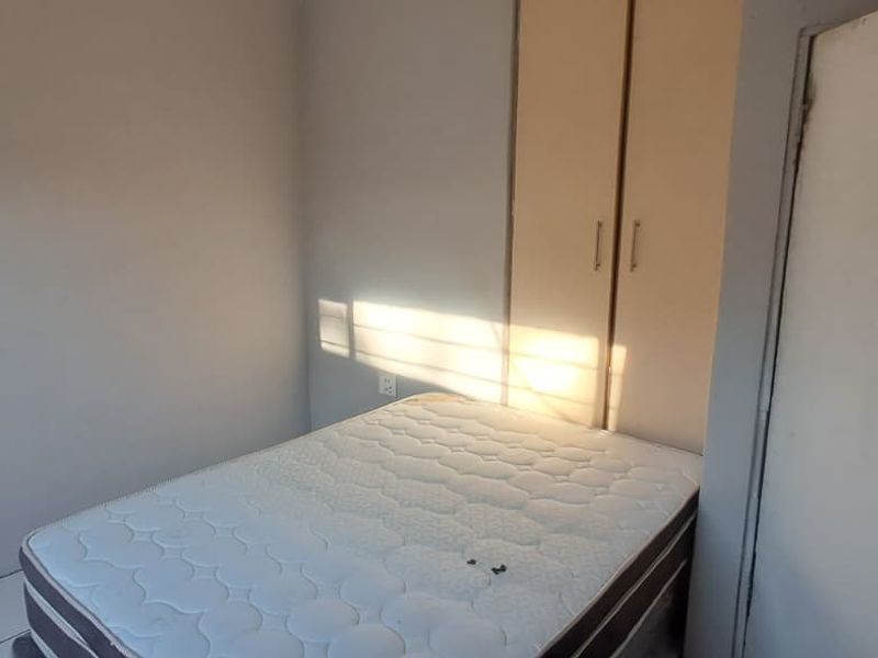 A compact bedroom featuring tiled flooring and a built-in wardrobe, offering a functional space ready for cosmetic updates.