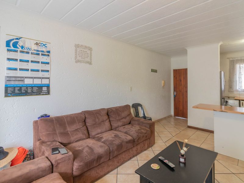 Open plan living area featuring tiled flooring and a breakfast bar connecting to the kitchen space.