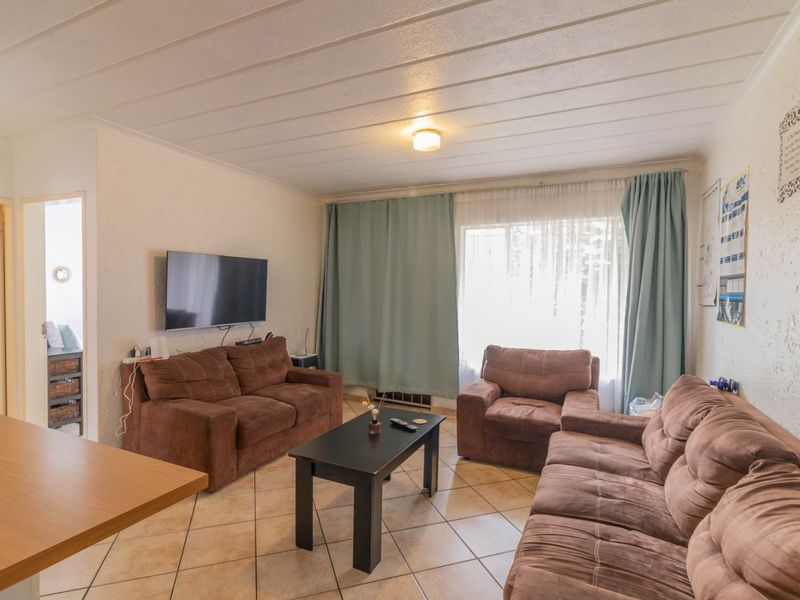 A functional living room featuring tiled flooring and a neutral ceiling, offering a comfortable space for relaxation and entertainment.