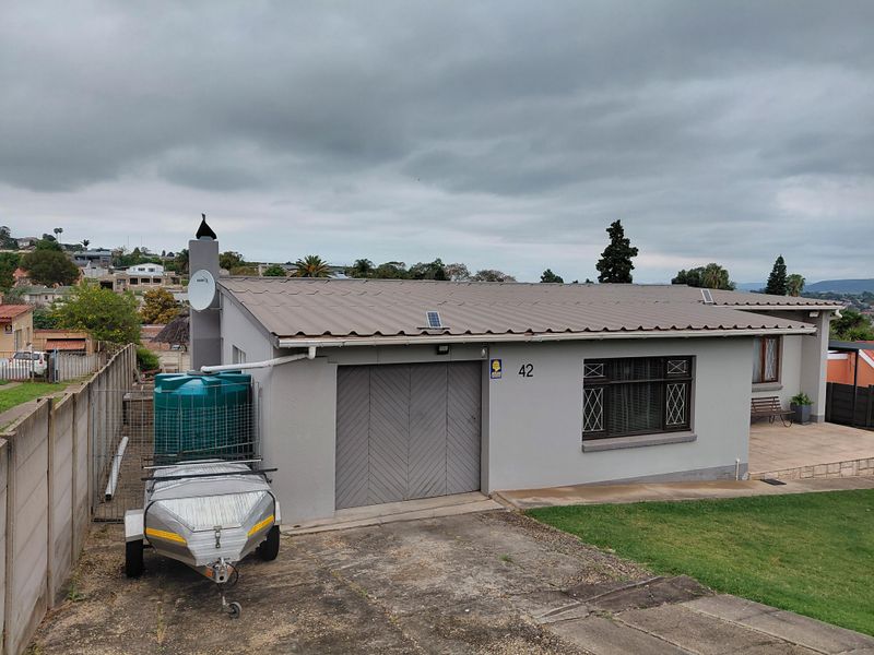 Front elevation of a single-story house featuring a metal roof, integrated garage, and paved driveway area.