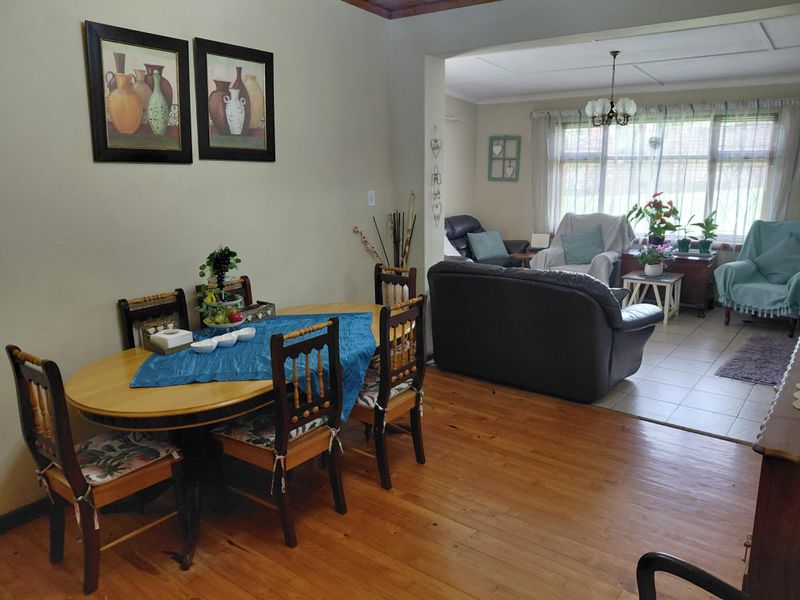 Open plan living and dining area featuring a combination of timber and tiled flooring with a central chandelier and ceiling fan.
