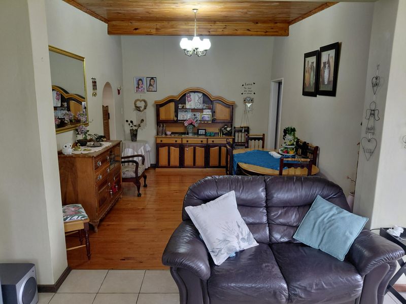 Open plan living and dining area featuring a combination of tiled and timber flooring with exposed timber ceiling beams.