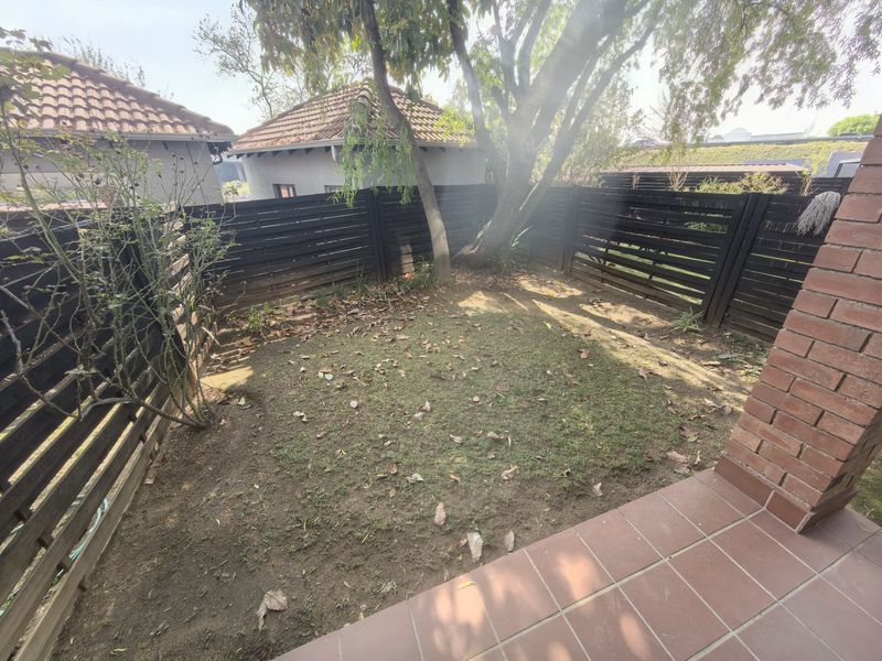 A private rear garden area featuring a tiled patio, brick pillar, and timber slat fencing, offering a compact outdoor space.