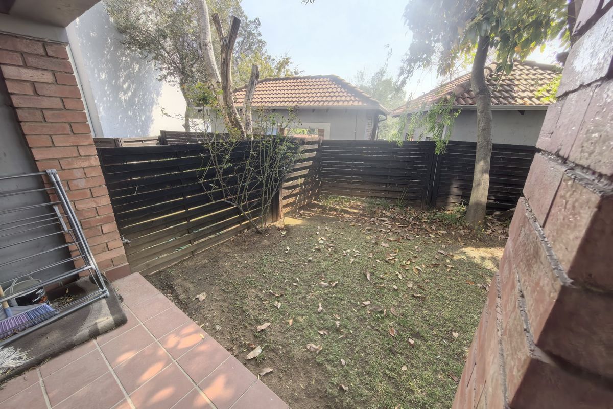 A private rear garden area featuring a tiled patio, lawn space, and perimeter timber fencing.