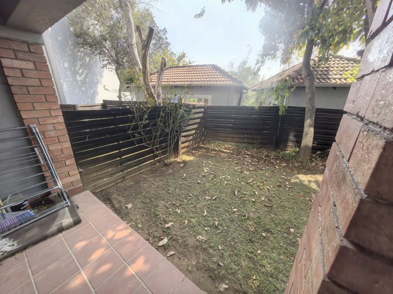 A private rear garden area featuring a tiled patio, lawn space, and perimeter timber fencing.