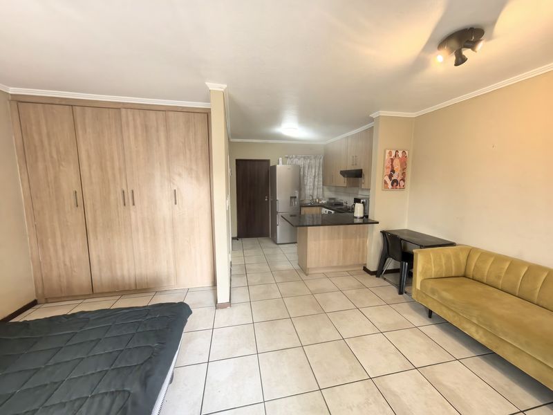 Open-plan living area featuring tiled flooring, built-in storage cupboards, and a functional kitchen with granite countertops and integrated cabinetry.